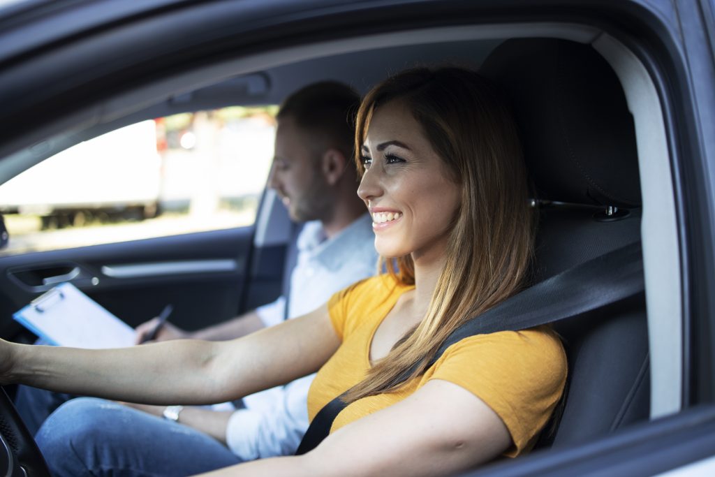 Élève au volant avec son moniteur qui tient une grille d’évaluation